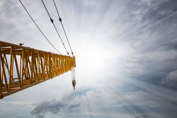 indotti e parapisti di sistemi di sollevamento gru a torre e c'è un cielo blu e un raggio di luce solare. - hoisting crane foto e immagini stock