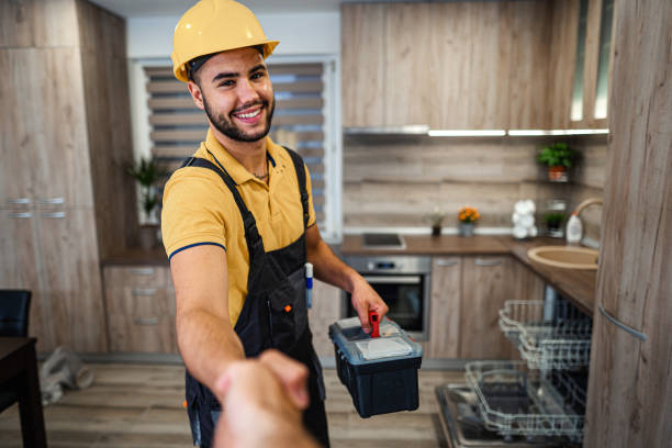 Young male plumber shaking hands in kitchen