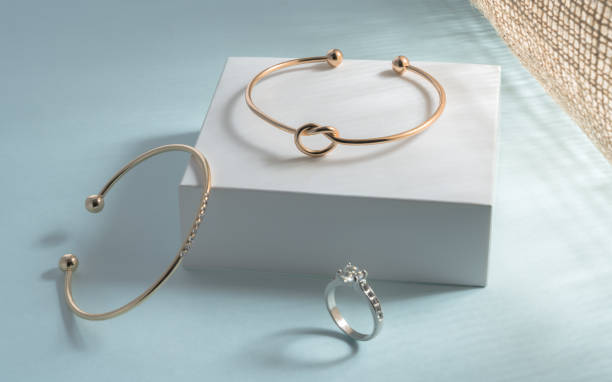 istock Gold modern bracelets and diamond ring on white and blue background under sun light 1331806363