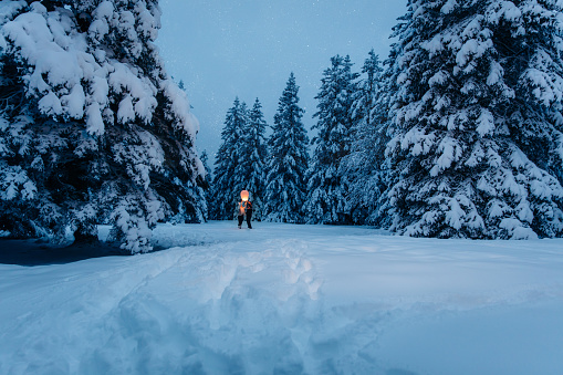 Couple holding sky lantern in snow covered forest