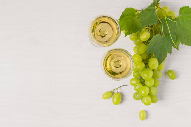 Glasses of white wine and white grape on wooden table top view. Glasses of white wine and white grape on wooden table top view. Wine composition with copy space for design. champagne grapes stock pictures, royalty-free photos & images