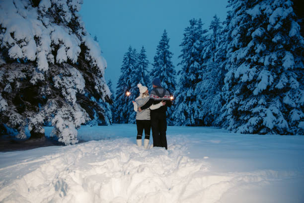 istock Couple embracing while holding sparkler on snow covered forest 1331808032