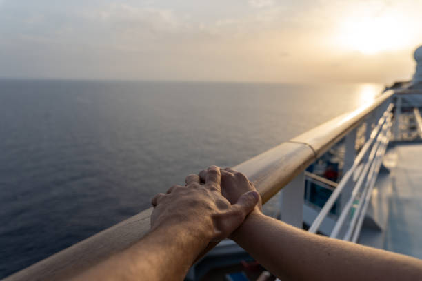 船の手すりに寄りかかっているカップルの手、背景に夕日 - trust human hand sea of hands holding ストックフォトと画像