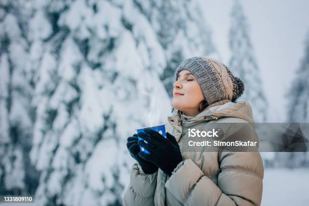 Young Woman Standing On Snow Covered Forest With Eyes Closed Stock Photo - Download Image Now