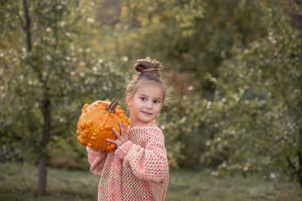 Family preparing for Halloween, two young girls making Jack-o-Lantern from pumpkins