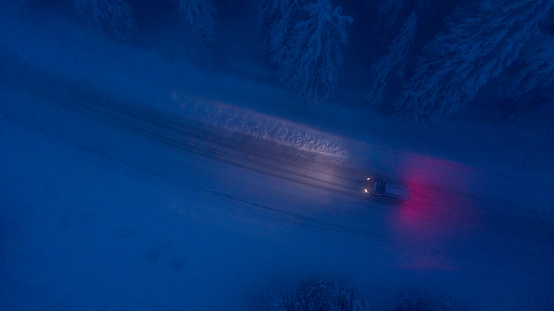High angle view of car traveling on road in snow covered forest at night
