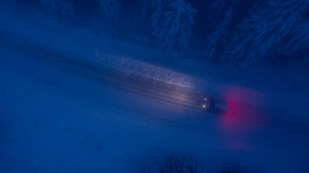 high angle view of car traveling on road in snow covered forest - vista aérea de carro isolado imagens e fotografias de stock