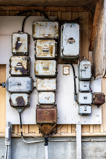 Outdoor closeup facade view of many old rusty worn electrical boxes and wires on building wall. Mounted on a old wooden building in Djurgården Stockholm Sweden.