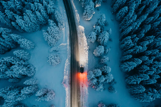 vue à angle élevé de la voiture sur la route dans une forêt enneigée - aerial view landscape scenics snow photos et images de collection