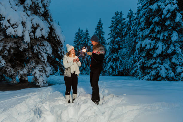 istock Couple holding sparkler in snow covered forest 1331811727
