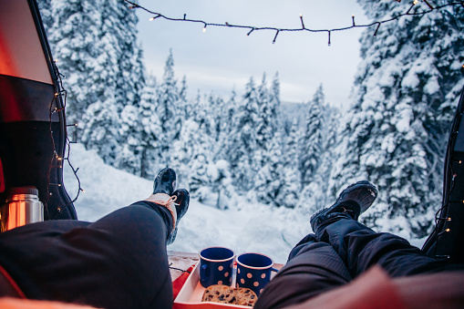 Couple resting in car trunk at snow covered forest