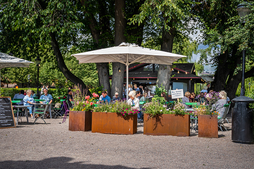 Stockholm, Sweden - July 20, 2021: Beautiful summer garden view of a small cafe with guests in the public city garden Kungsträdgården in Stockholm July 20, 2021.