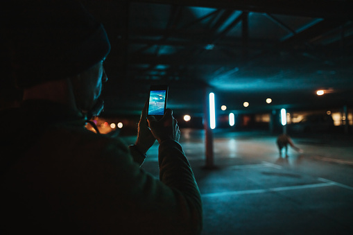 Man taking photo of his friend dancing using smartphone at parking lot