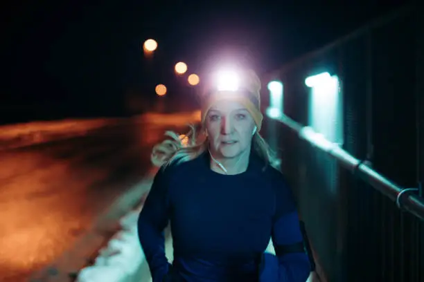 Portrait of woman jogging on street at night