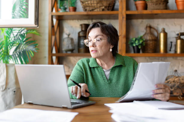 istock A mature woman while filling out documents. She uses an online tutorial to fill in the documentation correctly 1331814988