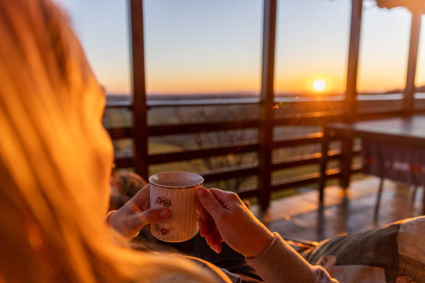 Woman holding tea cup and enjoying sunset