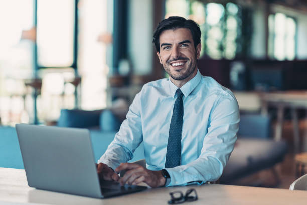 Smiling businessman with shirt and tie, using laptop