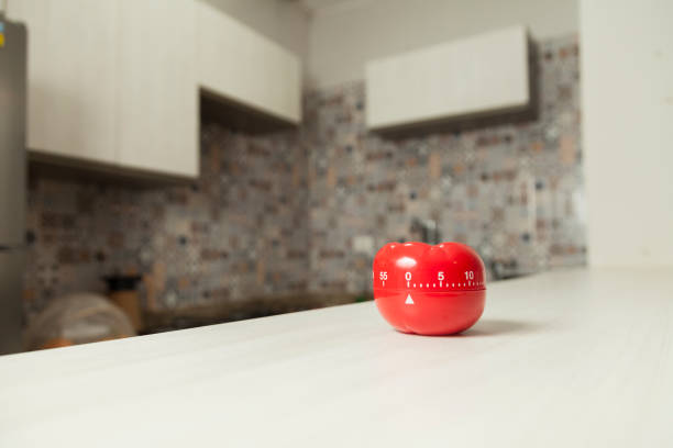 istock Red tomato-shaped kitchen timer with cooking in the background. 1331816459