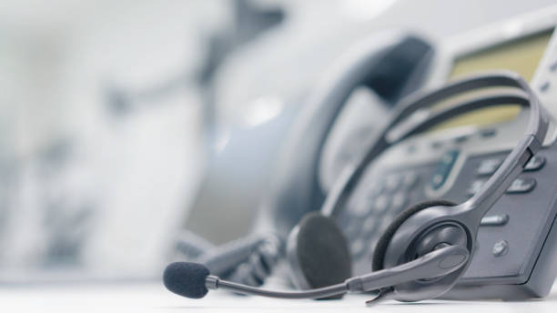 cierre los auriculares del centro de llamadas y voip para la tecnología de comunicación en la mesa de la oficina en la sala de monitoreo para el concepto de trabajo de operación de red - centro de llamadas fotografías e imágenes de stock