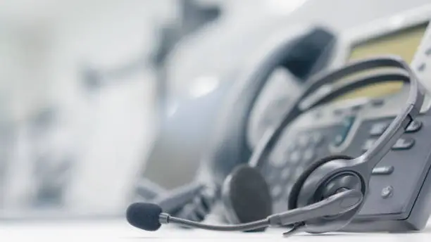 Photo of close up headset of call center and VOIP for communication technology on office table  in monitoring room for network operation job concept