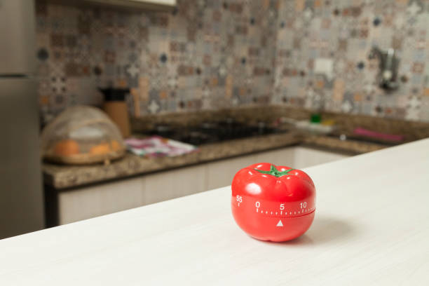 istock Red tomato-shaped kitchen timer with cooking in the background. 1331816582