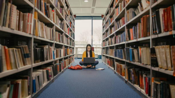 teenage girl using laptop in library - adult education full length book imagens e fotografias de stock