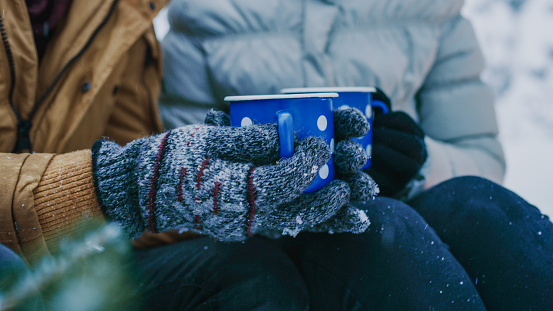 Midsection of couple holding coffee cup in winter