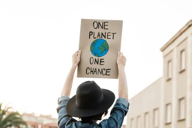 Photo of Demonstrator on the city protesting against climate change and pollution - Global warming and environment concept - Focus on banner