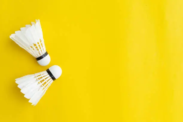 Photo of close up top view of white shuttlescocks on yellow color background with copy space for design,show content and promote banner for  sport concept