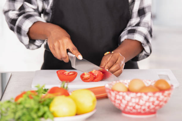 istock Afro american woman skillfully slicing tomatoes on a cutting board 1331825614