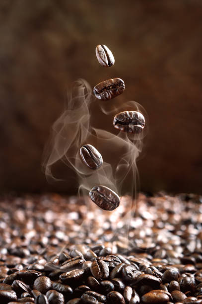 nahaufnahme fallender dampfender kaffeebohnen. selektiver fokus. das konzept der kaffeeröstung, hochwertige produkte. vertikale ansicht - falling beans stock-fotos und bilder