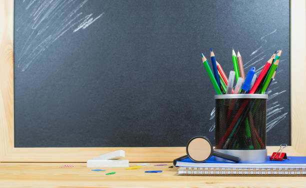 istock stationery in a plastic cup stand on a stack of notebooks on a wooden table against the background of a chalk board. back to school 1331834107