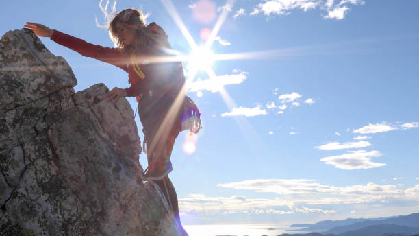 une jeune femme grimpe sur la crête ensoleillée de la montagne - 5895 photos et images de collection