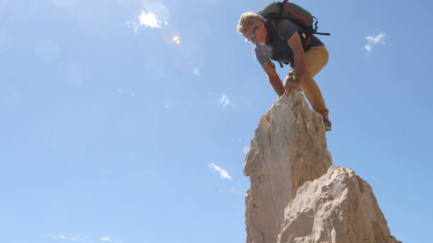 istock Mountaineer scrambles up sunny mountain ridge 1331835840
