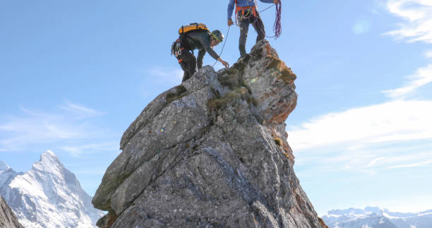 istock Mountaineers belay each other up mountain summit 1331838689
