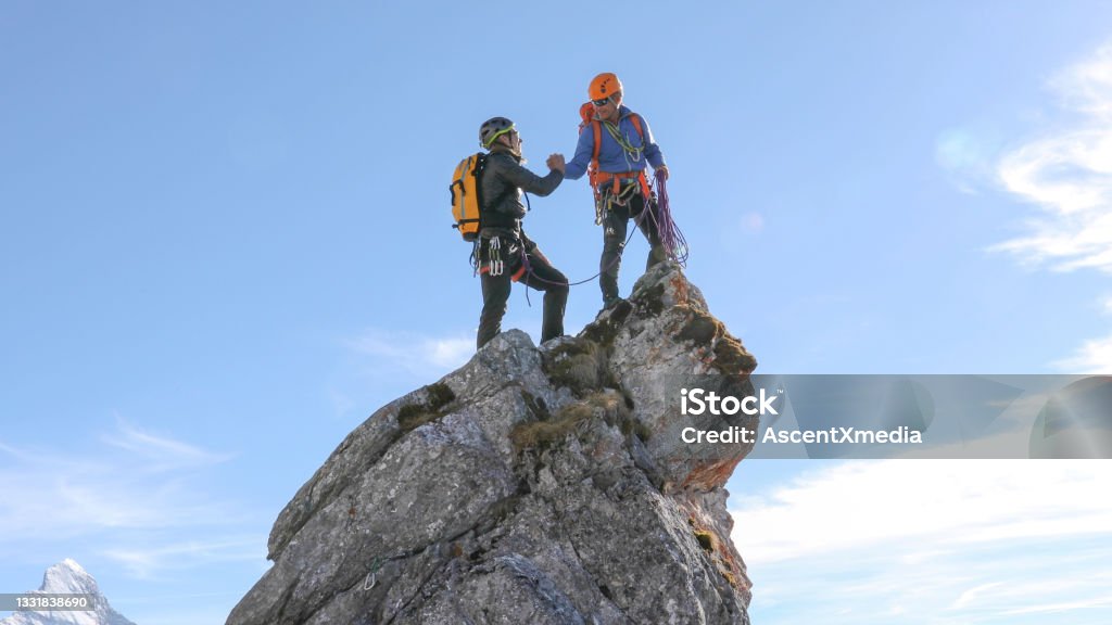 Mountaineers high five on mountain summit Monviso visible in the distant European Alps High-Five Stock Photo