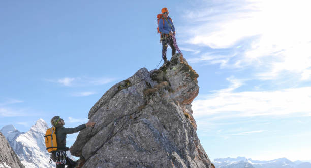 istock Mountaineers belay each other up mountain summit 1331838691