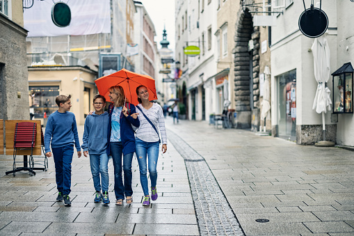 Mother and three kids sightseeing city of Salzburg in the rain