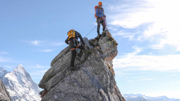 mountaineers belay each other up mountain summit - achievement mature adult adult mountain range imagens e fotografias de stock