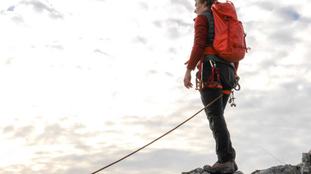 istock Mountaineer relaxes on mountain summit under lofty clouds 1331838953