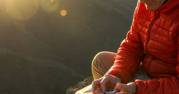 istock Mountaineer checks compass for direction on mountain summit 1331839856