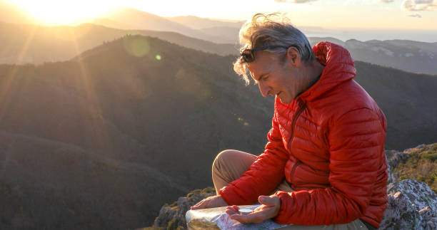 istock Mountaineer checks compass for direction on mountain summit 1331839908