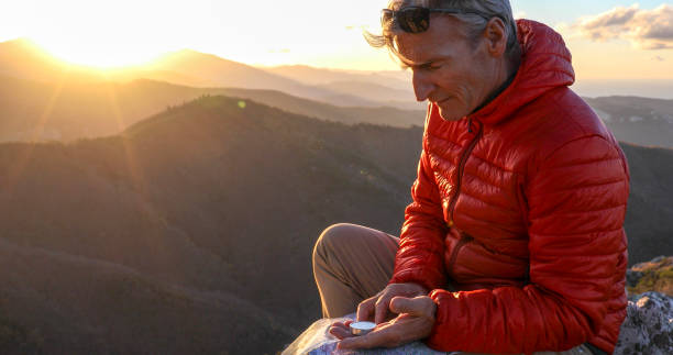 Mountaineer checks compass for direction on mountain summit
