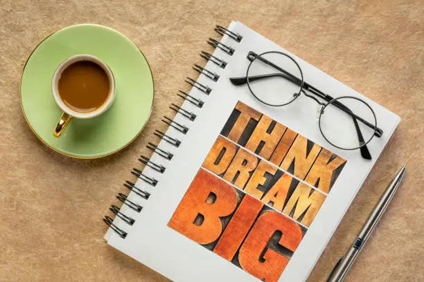think and dream big motivational phrase -  word abstract in letterpress wood type in a notebook with coffee