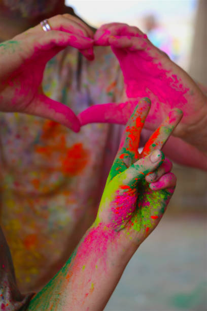 Hands, covered in vibrant colors, making heart and peace sign.  Conceptual image.