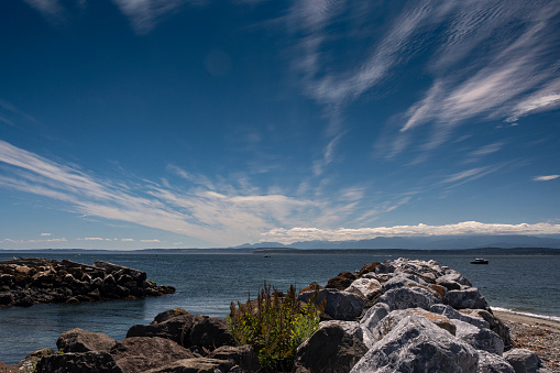 A rock jetty extending from the beach into Puget Sound on Whidbey Island in the state of Washington.  The jetty protects an inlet leading to several canals in an area known as Lagoon Point.  The Olympic Mountains on the Olympic Peninsular are visible in the distance.