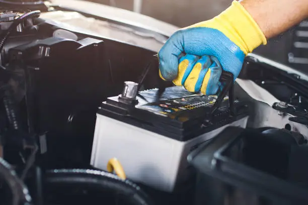 Technician is pulling up an car old battery for replacement