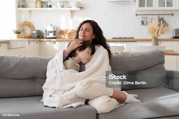 Young Mom Sit On Cozy Couch Relax With Preschool Son Covered With Blanket On Weekend Morning At Home Stock Photo - Download Image Now