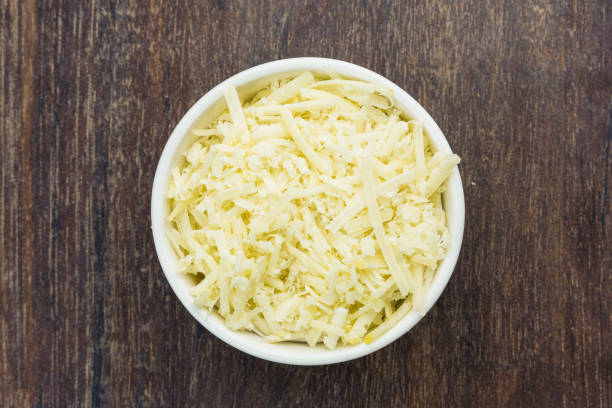 istock Grated cheese in a white pot isolated on a wooden cutting board. Selective focus. Top view 1331853506