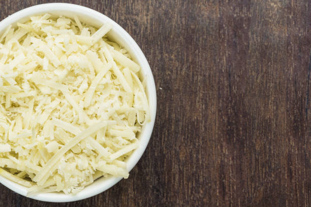istock Grated cheese in a white pot isolated on a wooden cutting board. Selective focus. Top view 1331853507